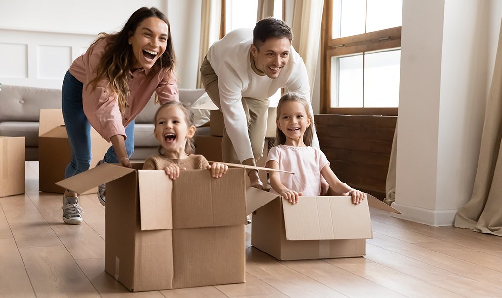 Happy parents playing with daughters in new apartment