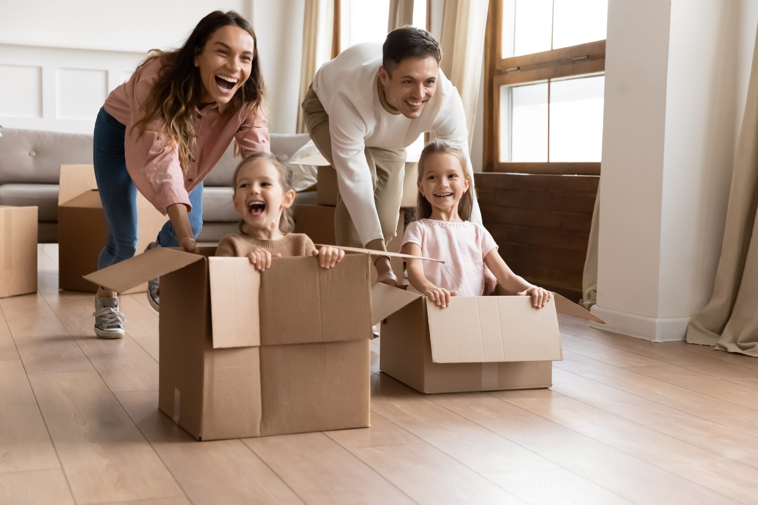 Happy parents playing with daughters in new apartment