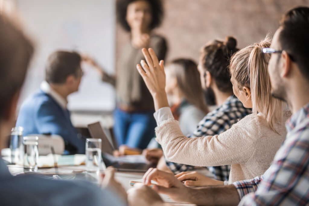 Businesswoman raising her hand to ask a question on a business meeting in the office.